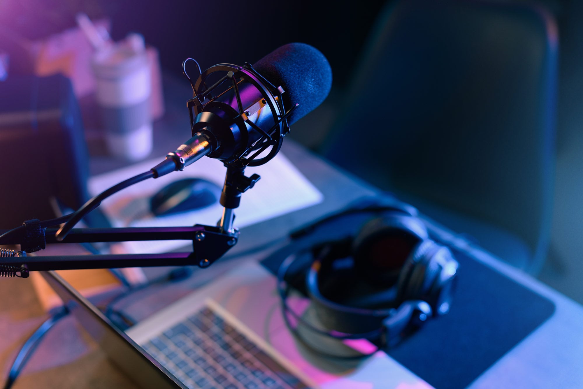 Image of studio microphone and headphones at a desk.
